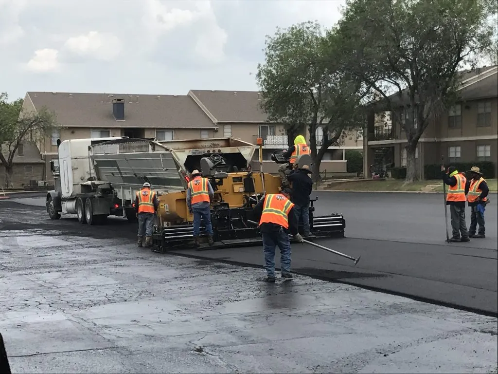 Arrow Asphalt crew paving apartment parking lot with asphalt paving equipment.