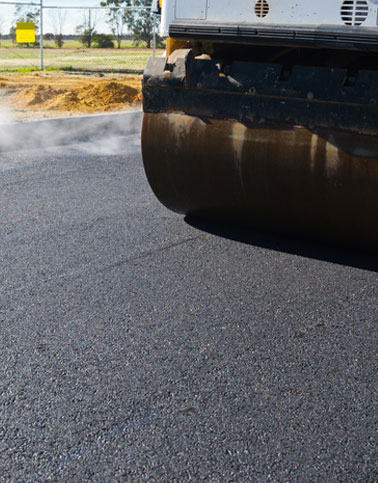 Asphalt paving roller compacting new construction surface