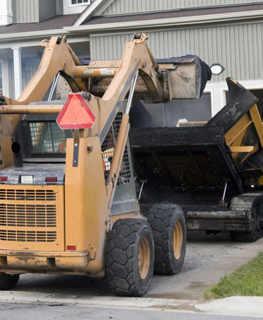 Asphalt paving equipment working on residential driveway installation.