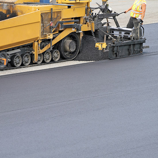 Asphalt paving equipment laying new asphalt for commercial parking lot installation.