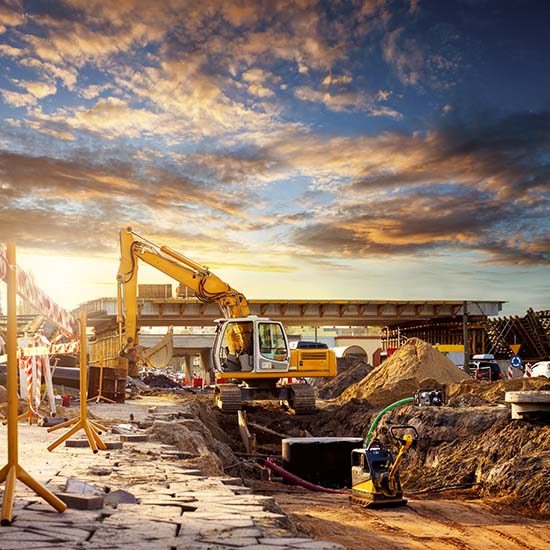Construction site with excavator and asphalt paving equipment for new road construction.