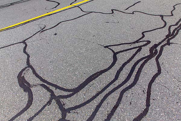 Asphalt parking lot surface with visible cracks needing crack filling repair.