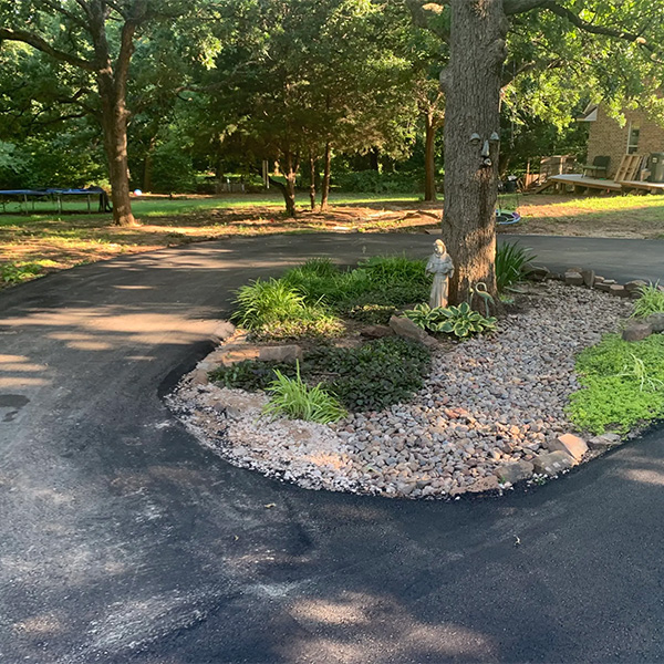 Newly paved asphalt driveway in Del City, OK, with landscaping and stone edging.