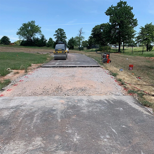 Asphalt repair and paving in Slaughterville, OK with roller compactor on new construction driveway.